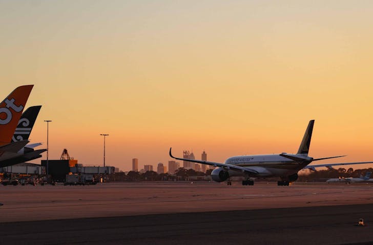 A wide shot of a plane beginning to prepare itself for take-off on the runway. It is either sunrise or sunset, and the sky is clear. 